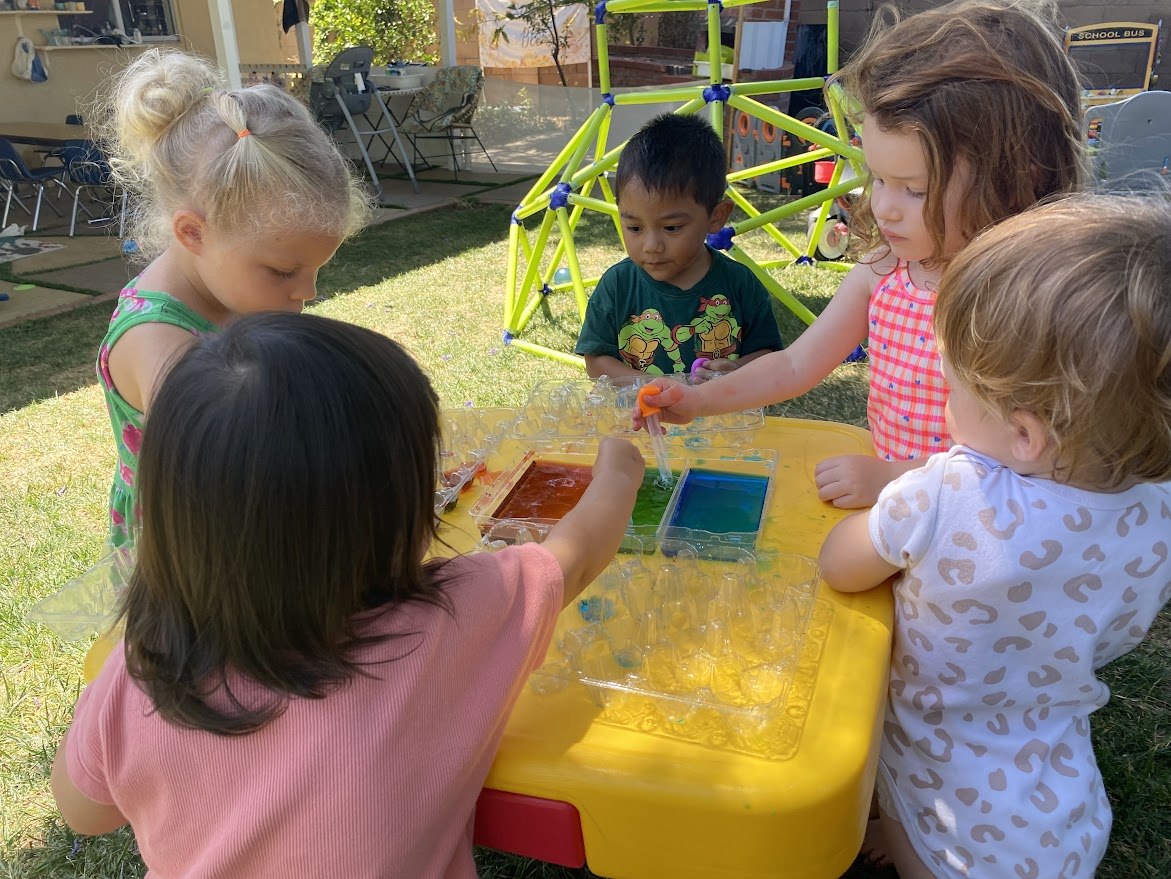 Children mixing colorful water outdoors