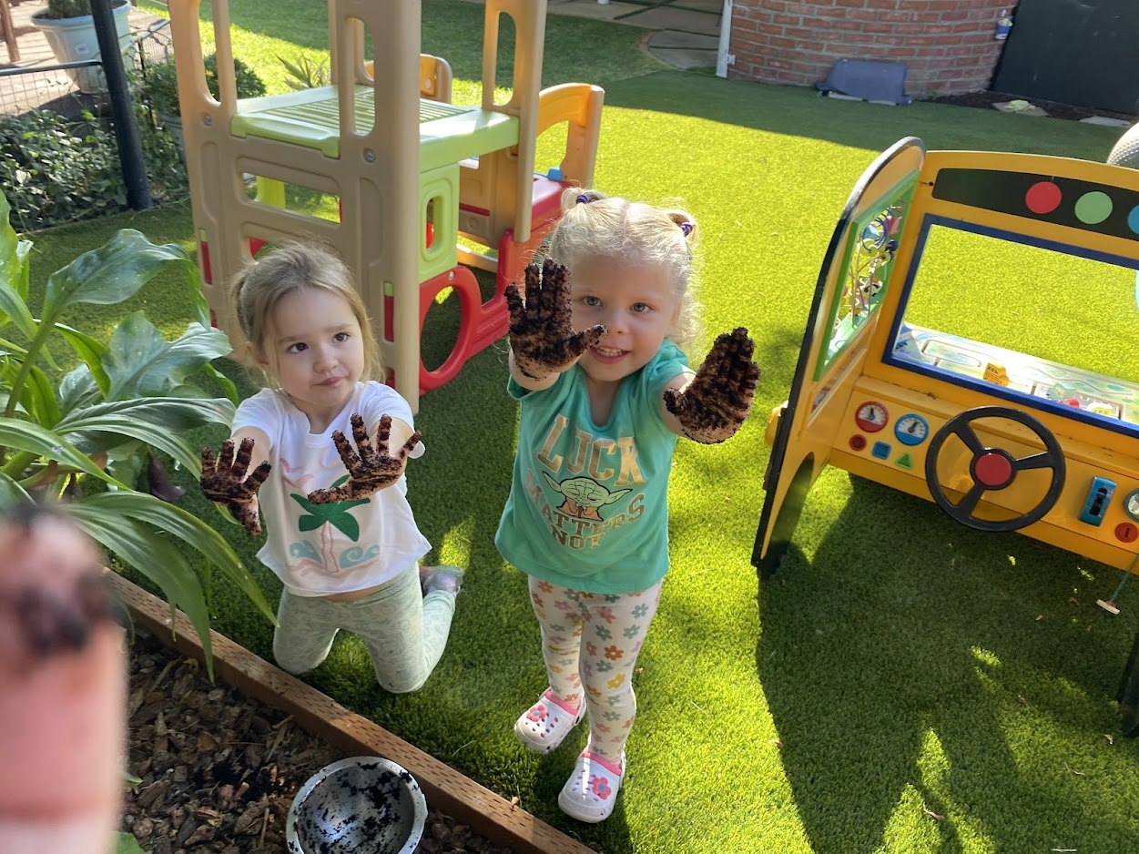 Children exploring a garden with messy hands